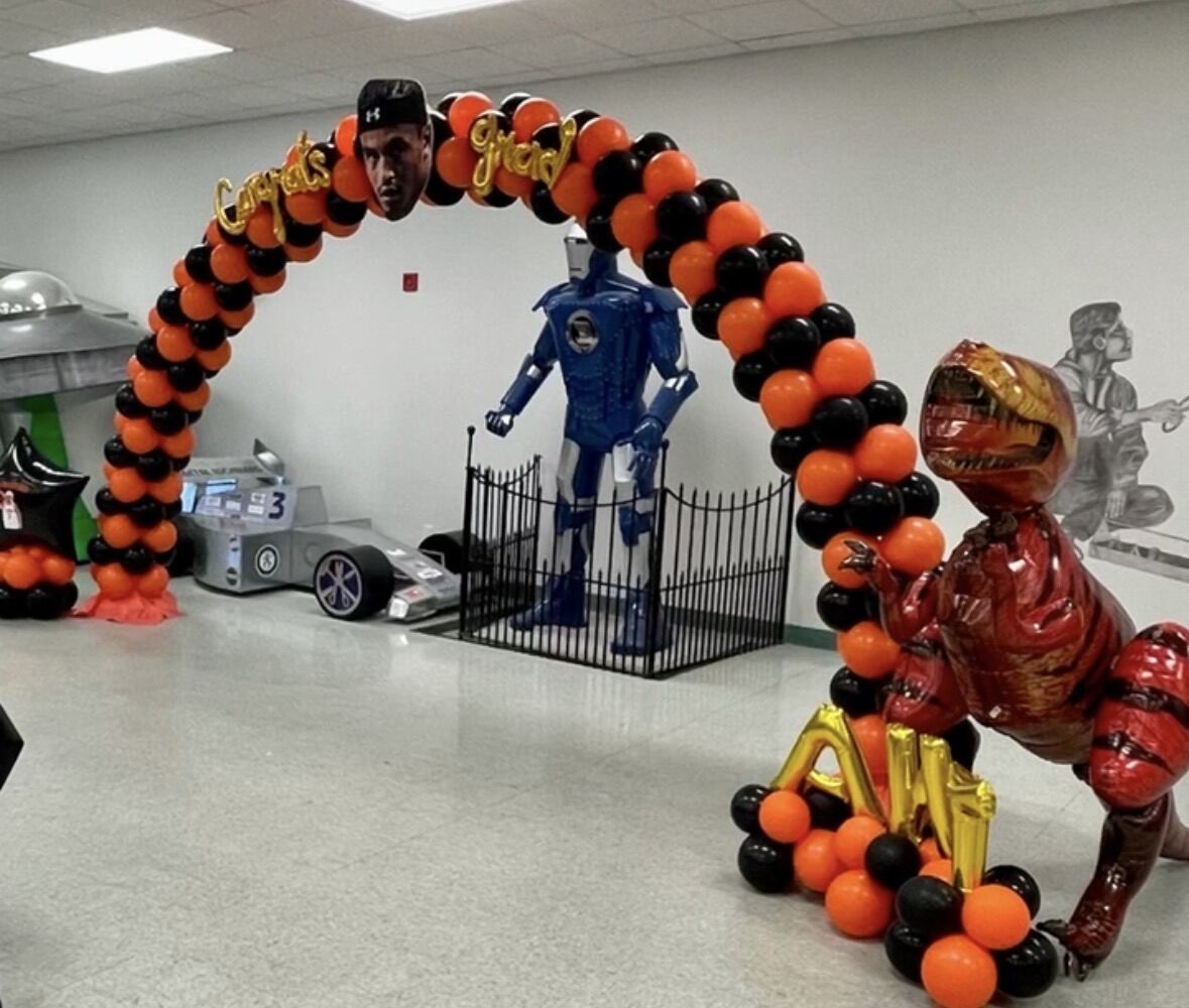 Orange and black superhero and dinosaur themed balloon arch