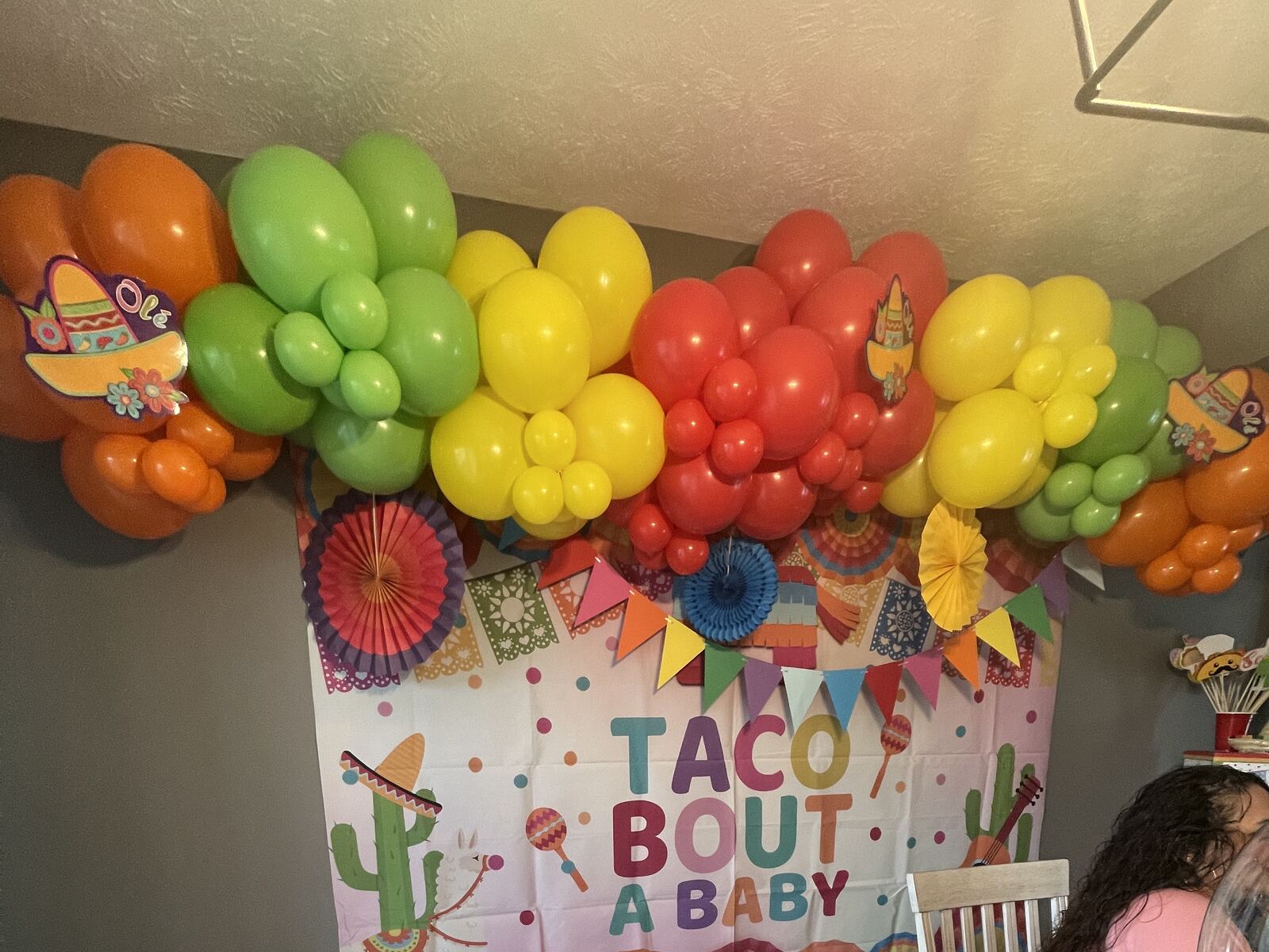 A colorful fiesta-themed balloon garland along a ceiling