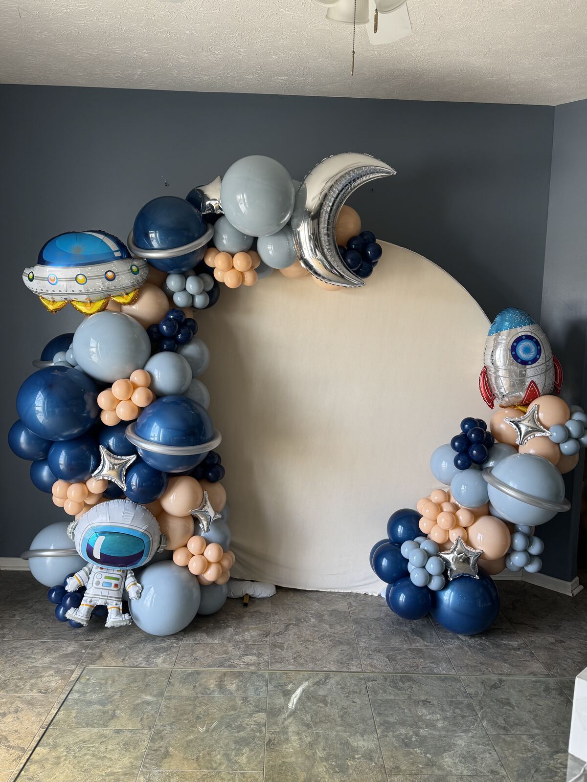 Blue, silver, and peach space-themed balloon archway with astronaut and rocket