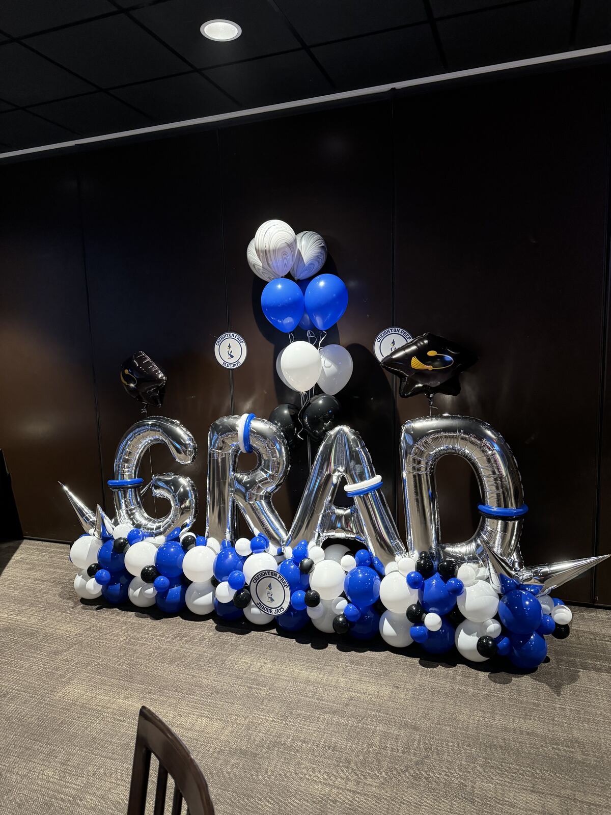 A silver GRAD balloon marquee stack with blue, black, and white balloons